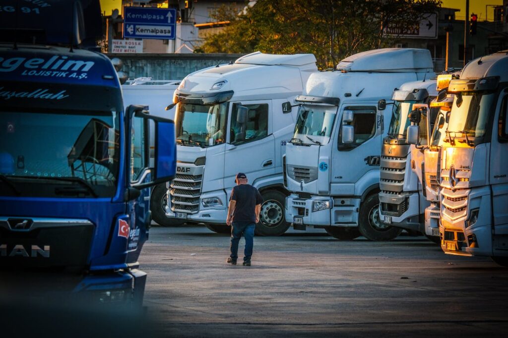 pexels photo 35097902 A man walks among parked trucks at sunset in an industrial area, creating a serene yet busy scene.