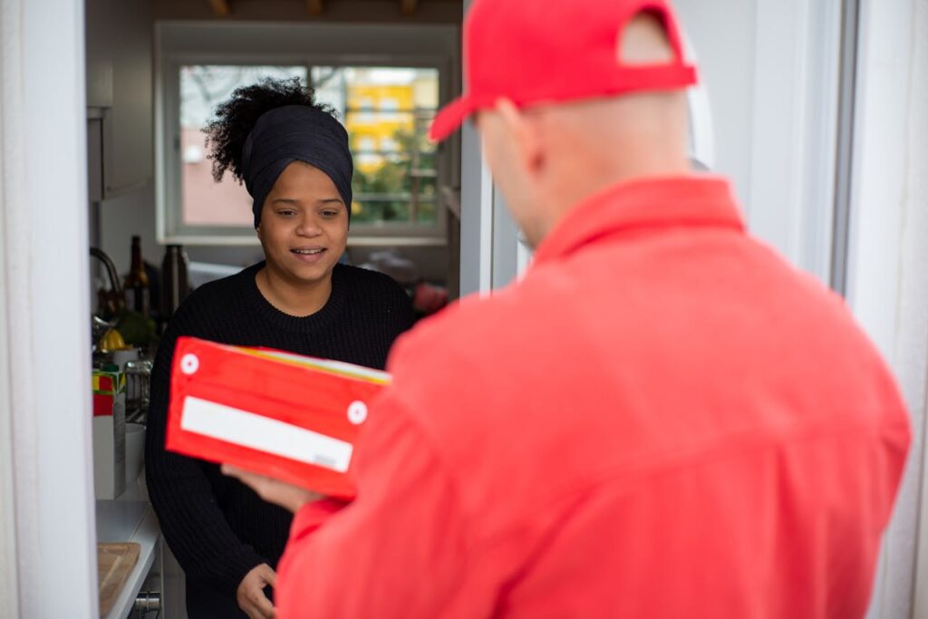 Courier delivers a package to a smiling customer at home, capturing a friendly interaction.